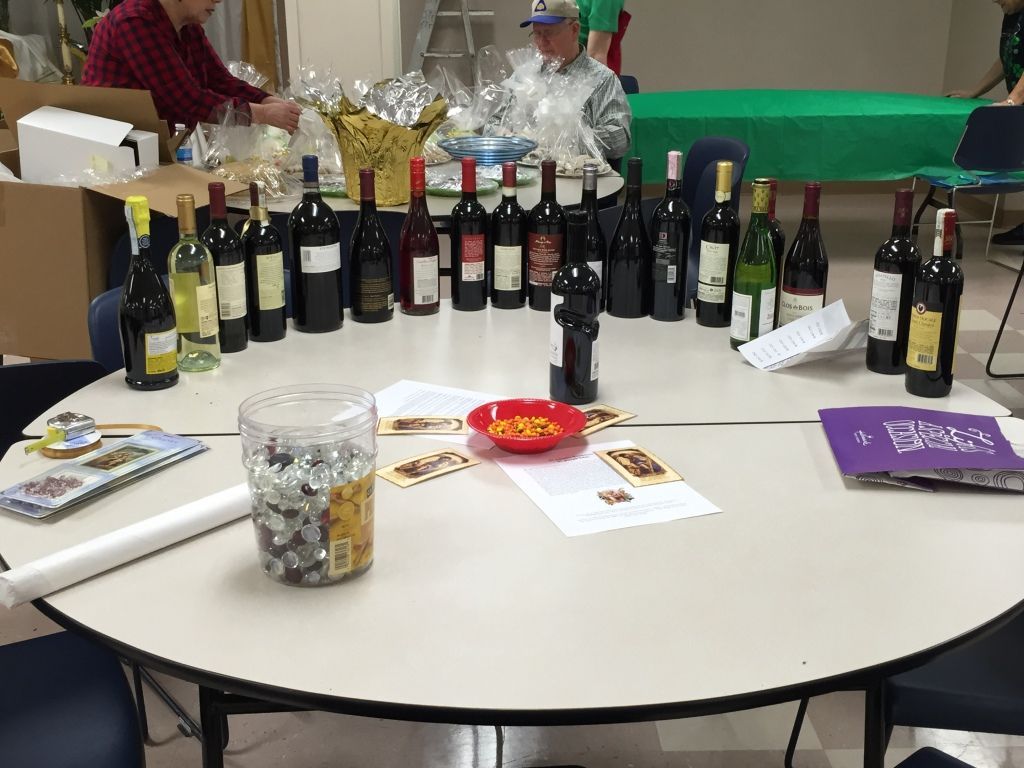 Circular table with assorted wine bottles, scattered papers, and a candy dish. 