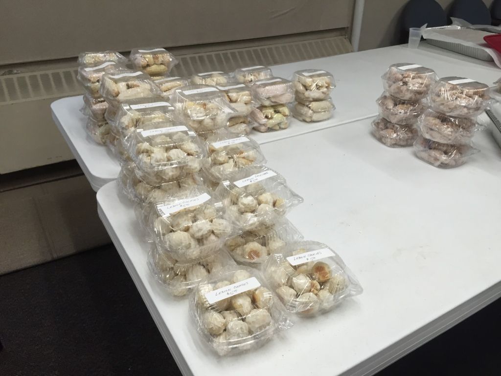 Rows of clear plastic containers filled with assorted pastries, neatly stacked on a white table.