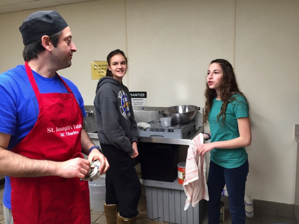 Three people standing in a kitchen.