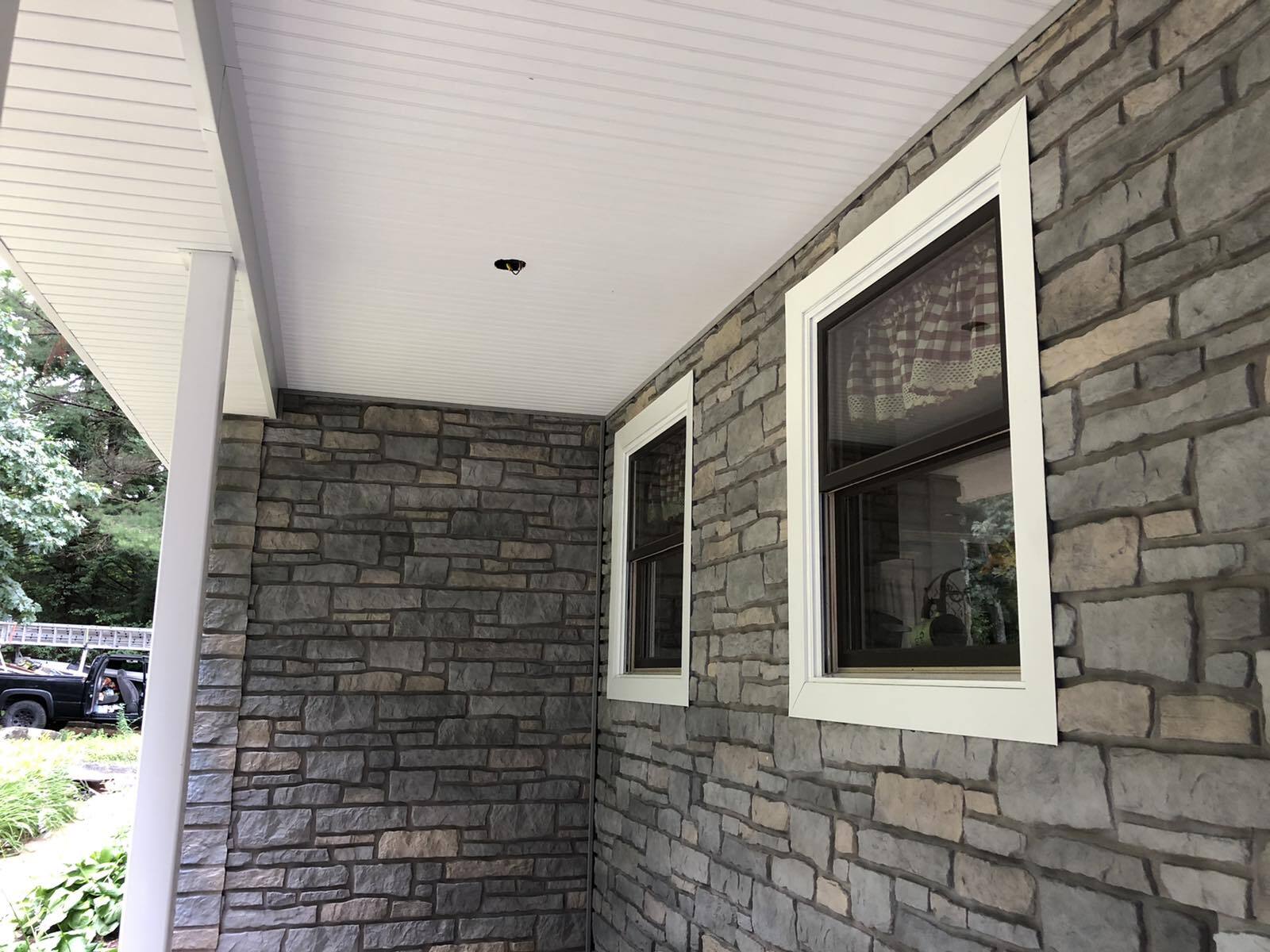 Gorgeous imitation stone made from vinyl installed for porch and complimented by white trim for windows.