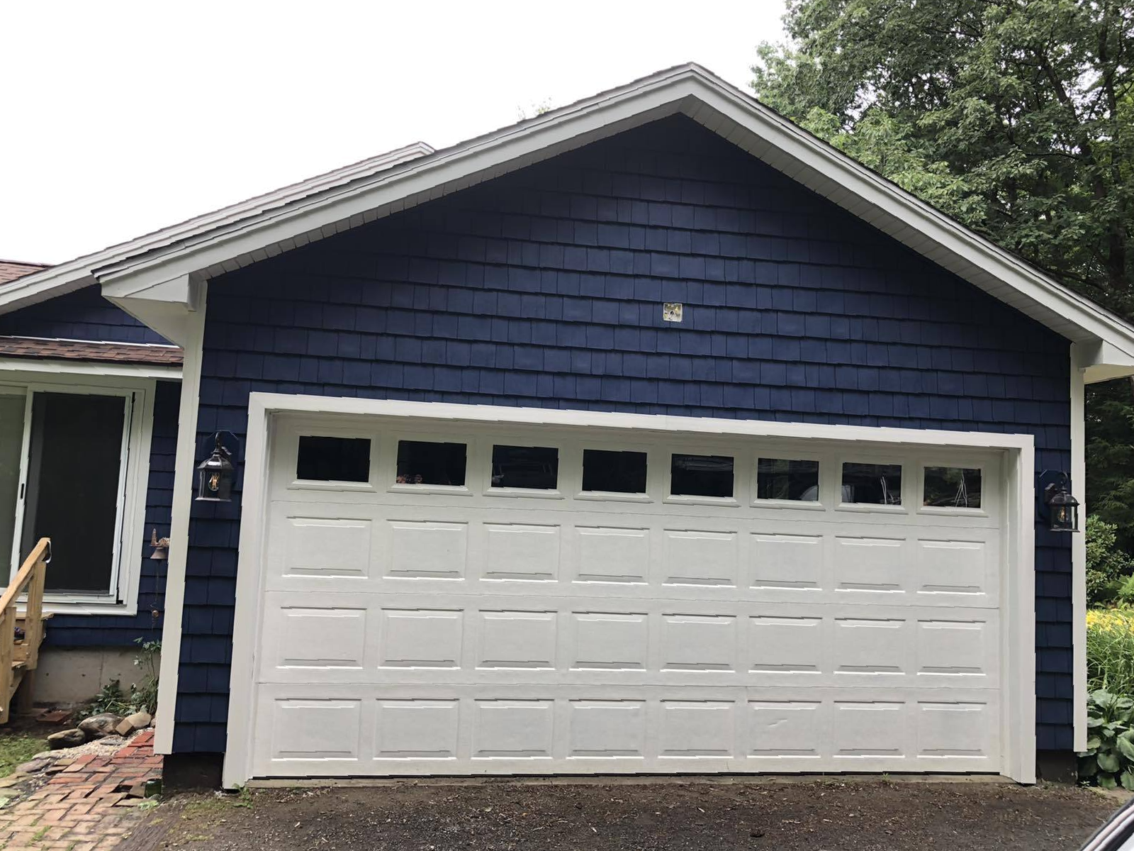 Garage sided with new dark blue shake vinyl siding and white trim for complimentary.