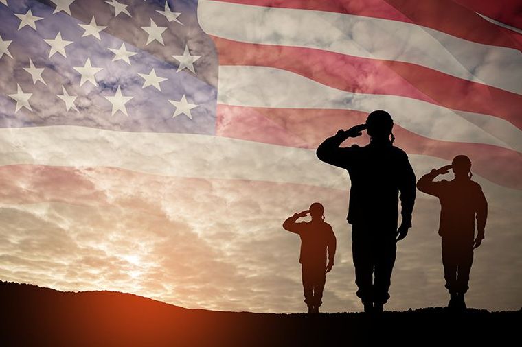 A group of soldiers saluting in front of an american flag.