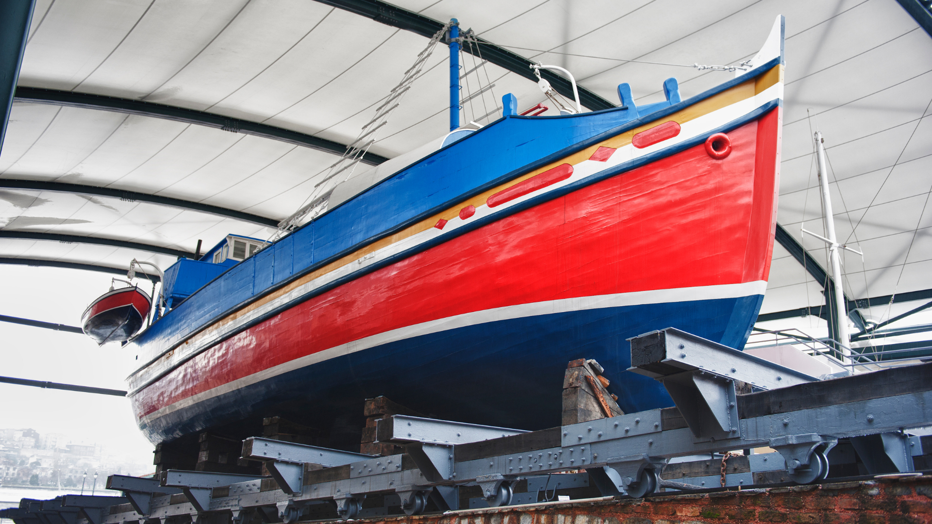 Blue and red boat on supports inside a building.