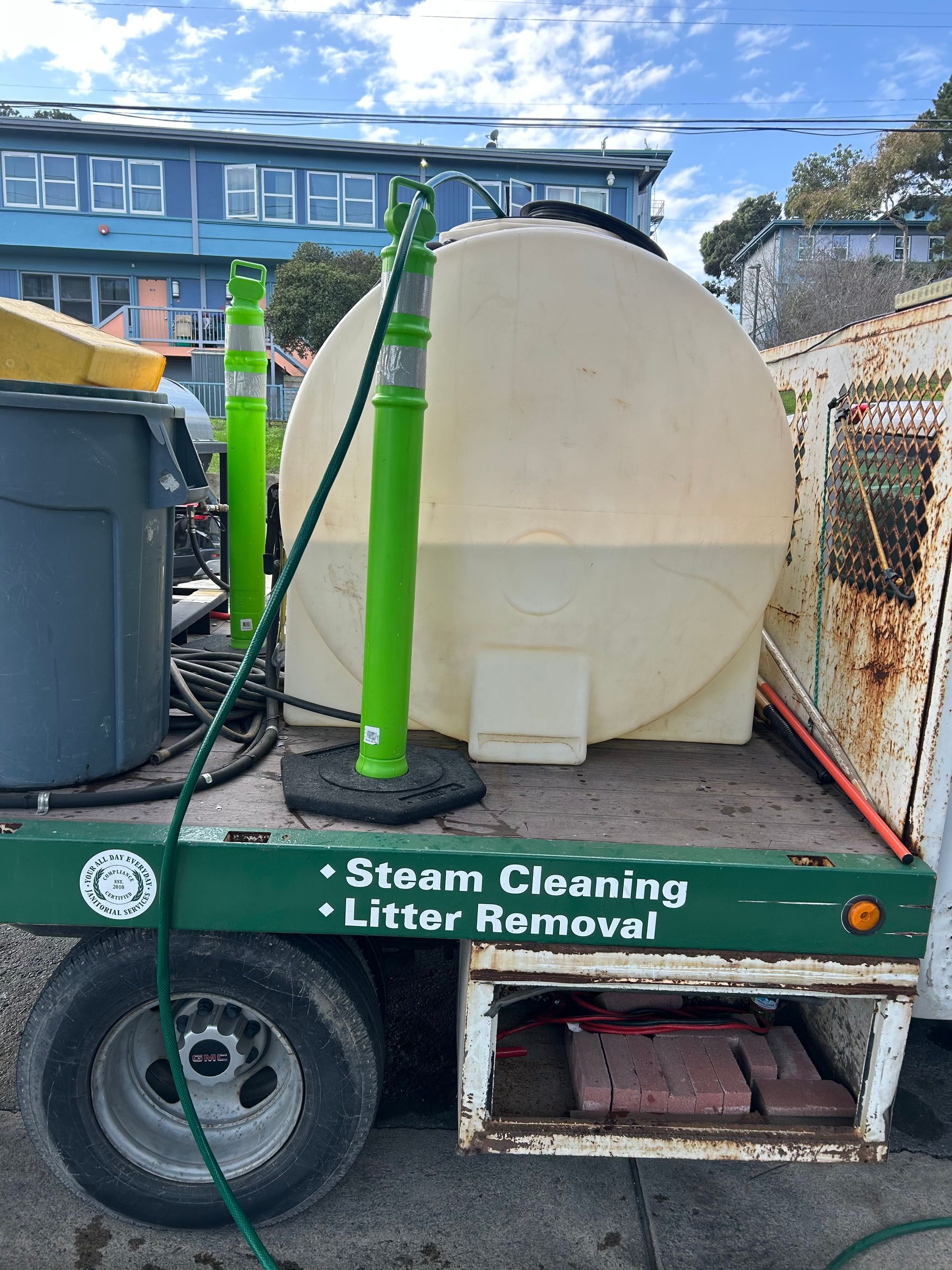 A trailer with a water tank for steam cleaning and litter removal; green and tan colors.