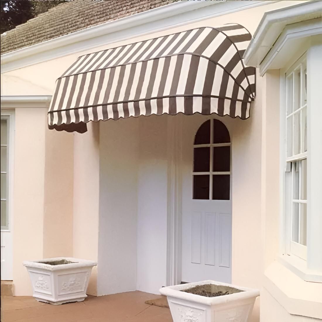 A House With a Striped Awning Over the Door — Port Blinds & Awnings In Port Macquarie, NSW