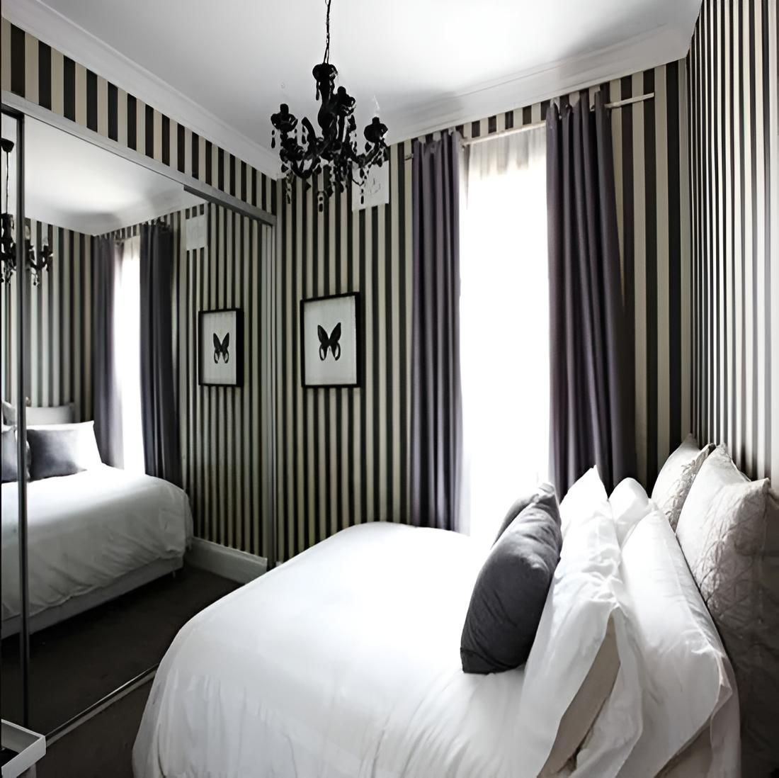 A Bedroom With Striped Walls and a Large Bed — Port Blinds & Awnings In Port Macquarie, NSW