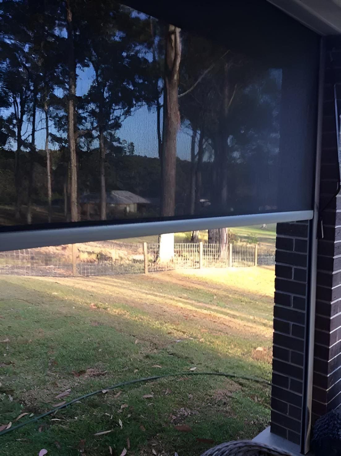 A Screened in Porch With a View of a Field and Trees — Port Blinds & Awnings In Port Macquarie, NSW