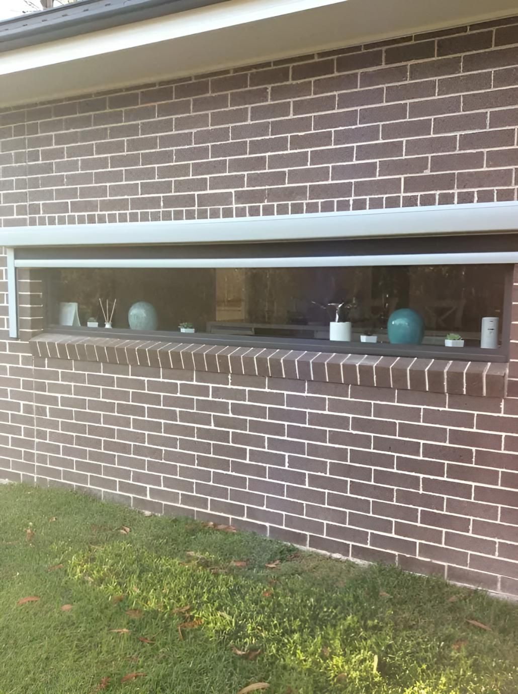 A Brick Wall With a Large Window in It — Port Blinds & Awnings In Port Macquarie, NSW