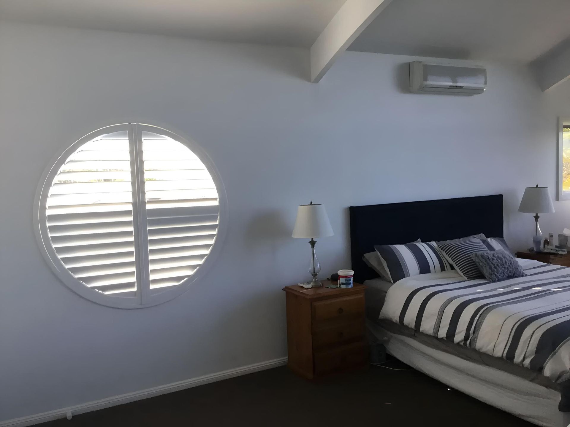 A Bedroom With a Round Window and a Bed — Port Blinds & Awnings In Coffs Harbour, NSW