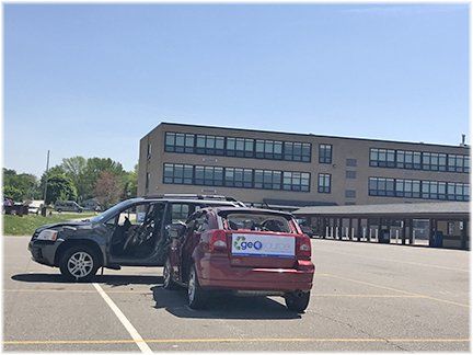 Two cars are parked in a parking lot in front of a building.