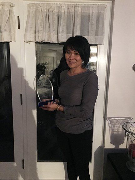 A woman is holding a trophy in front of a door.