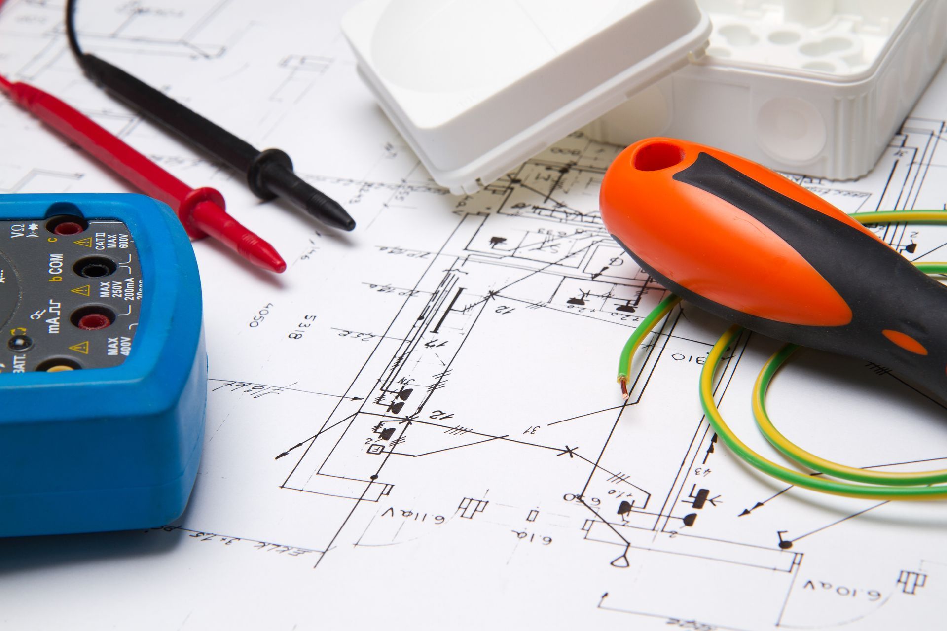 Electrical tools, including a multimeter and screwdriver, on a blueprint.