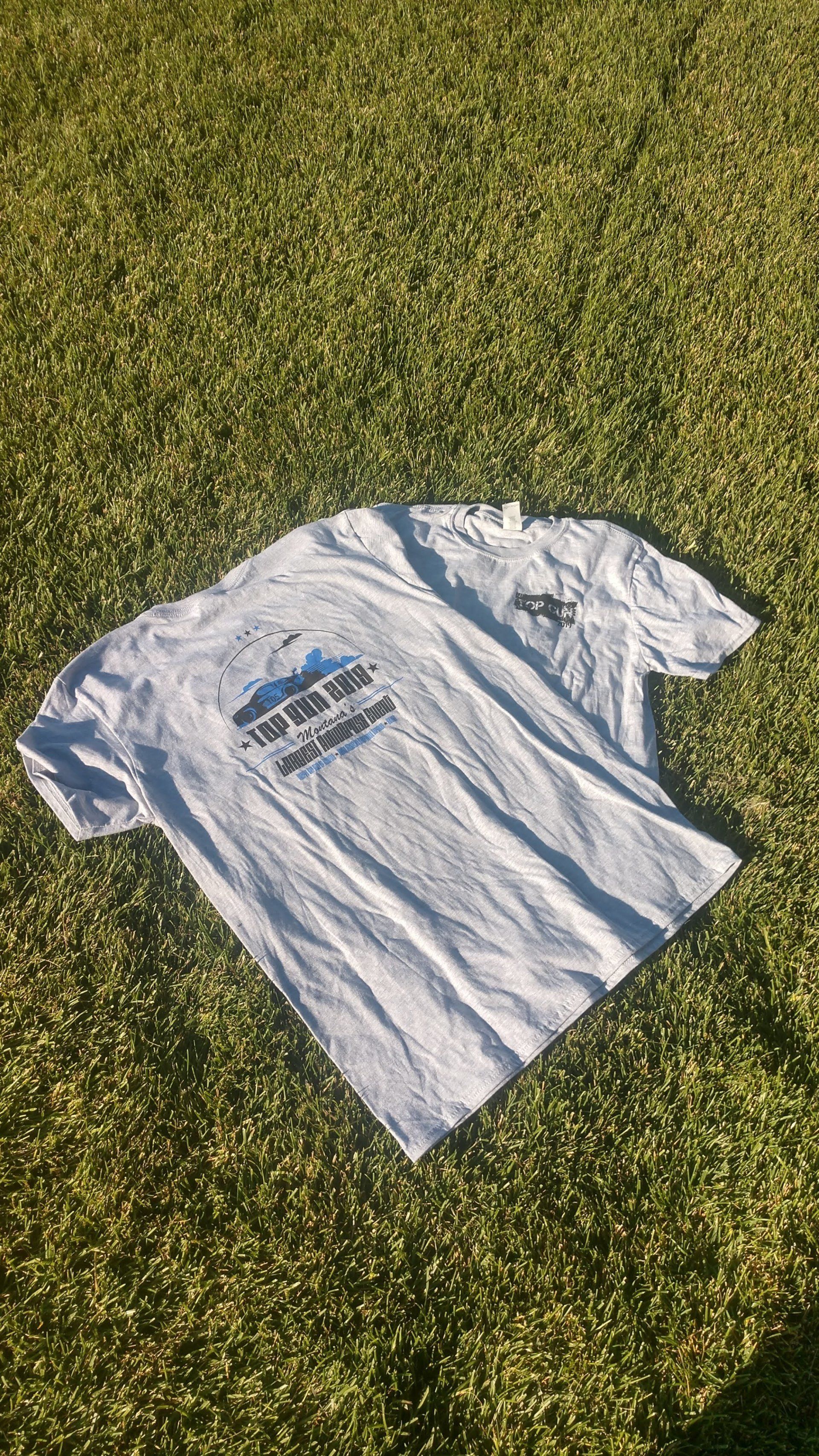 A white t-shirt is laying on top of a lush green field.