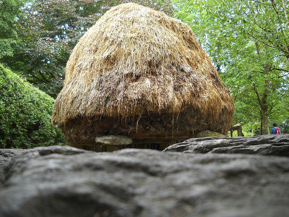 A large pile of hay is sitting on top of a pile of rocks.