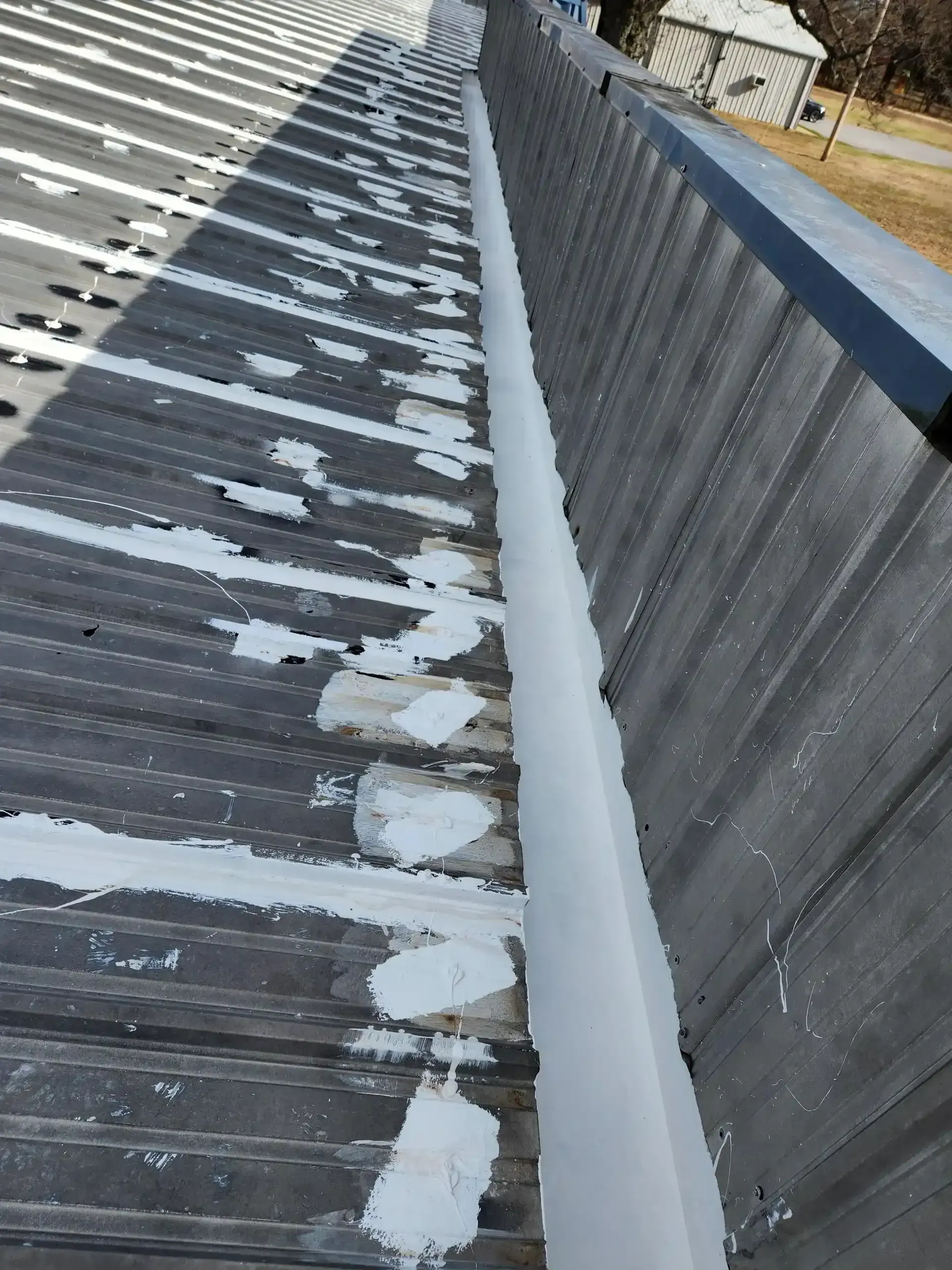 A gutter on the side of a building with white paint on it.