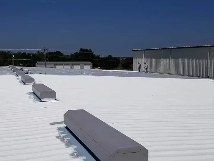 The roof of a building with a white roof and a blue sky in the background.