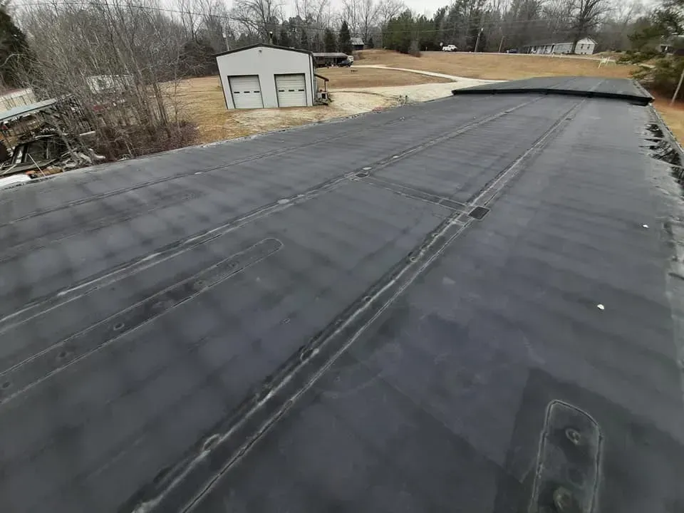 A black roof with a garage in the background.