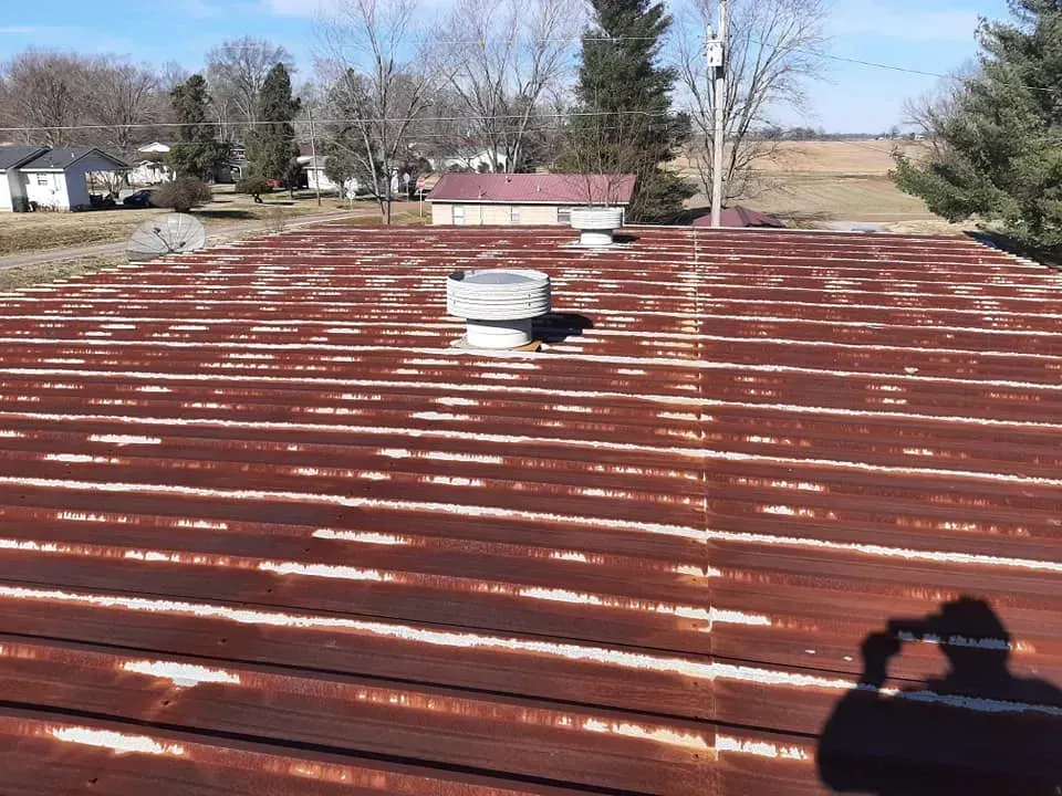 A person is taking a picture of a rusty roof.