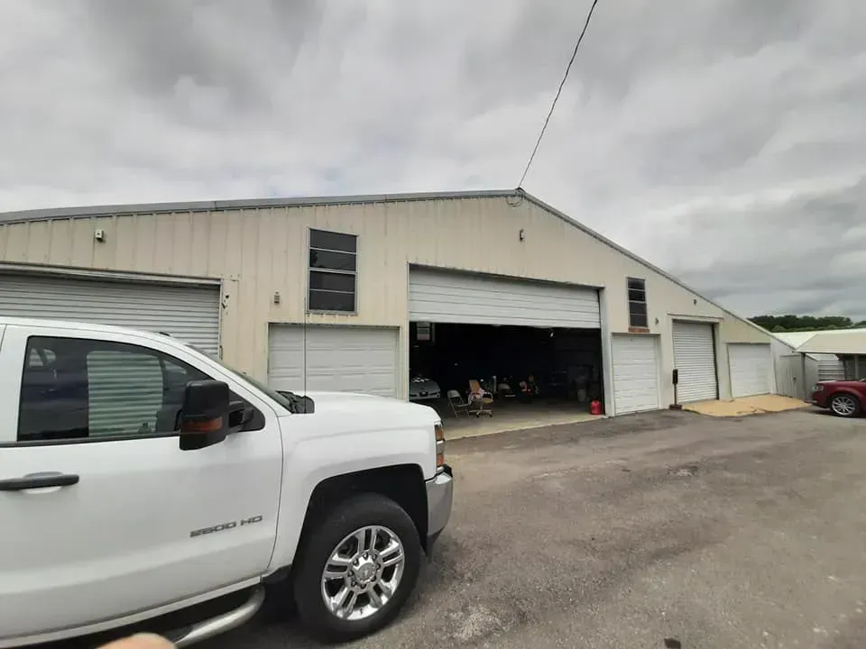 A white truck is parked in front of a garage.