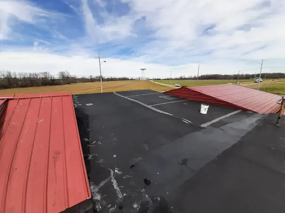 A red roof is sitting on top of a black asphalt parking lot.