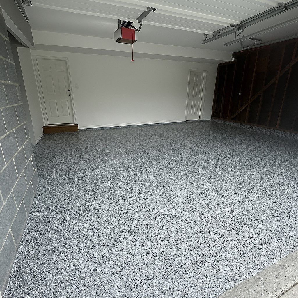 Empty garage with speckled gray epoxy flooring, white walls, and two doors.