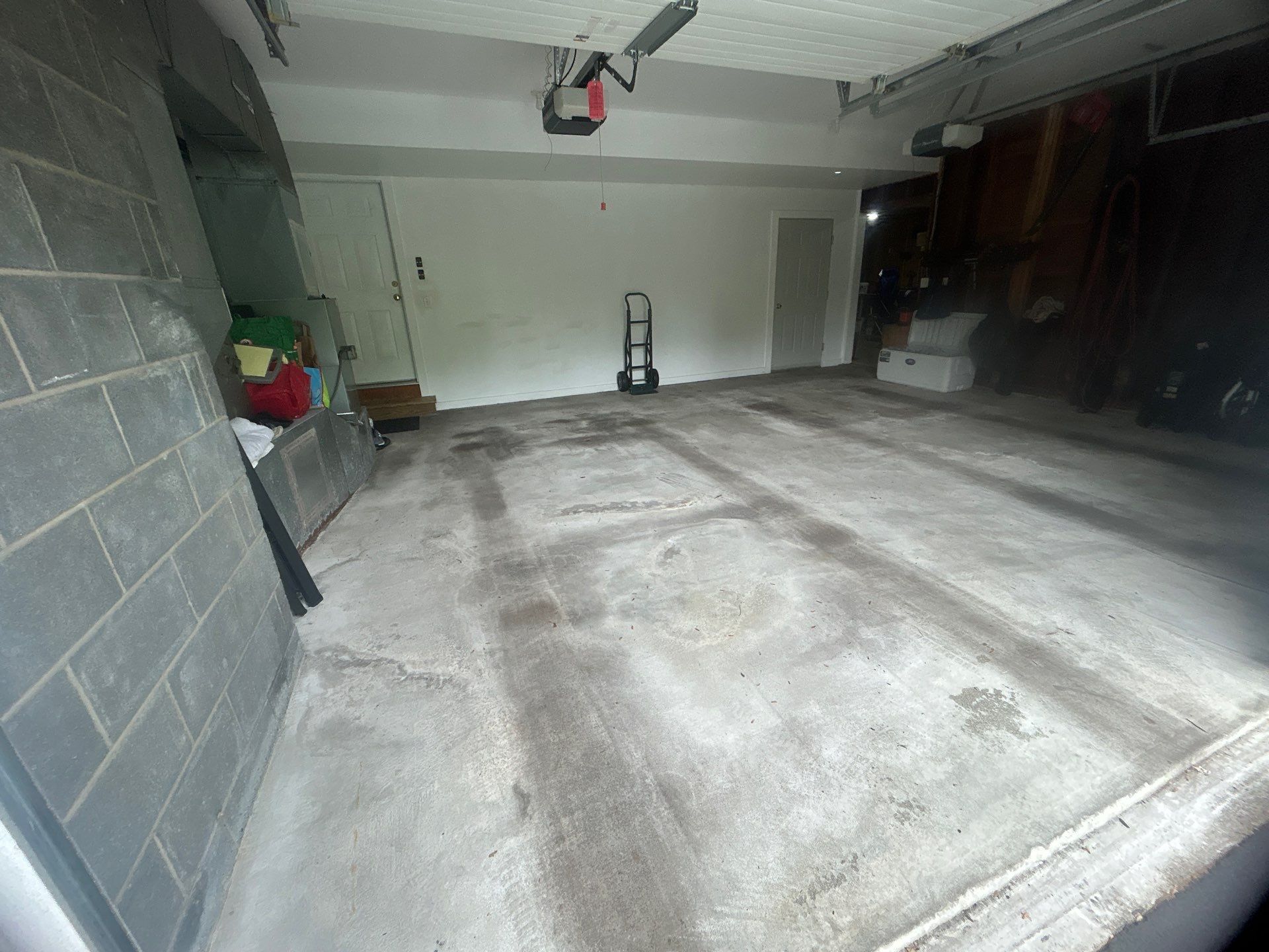 Empty garage with concrete floor, door and a vacuum cleaner.
