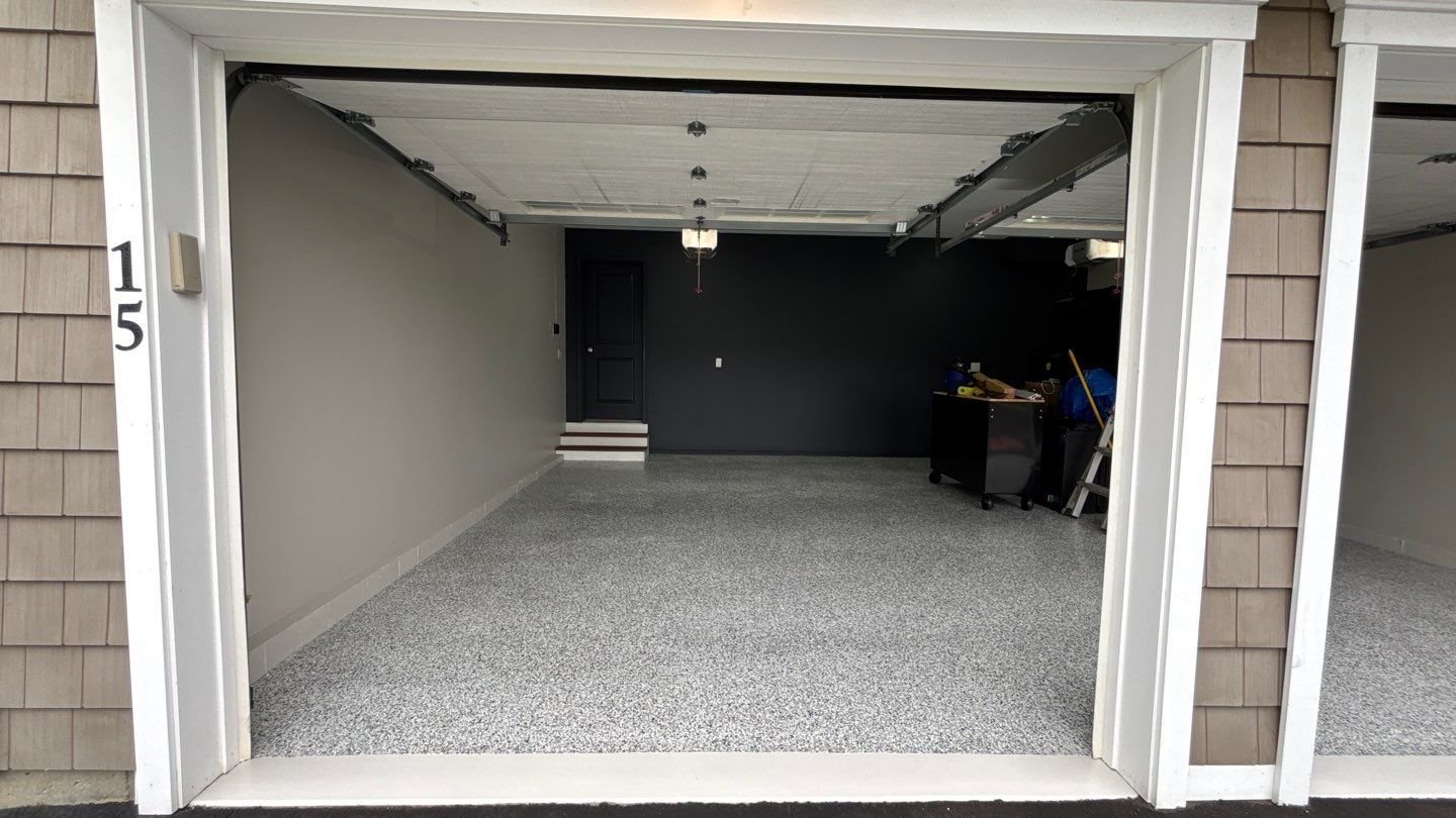 Garage interior with speckled floor, gray walls, and open doorway.