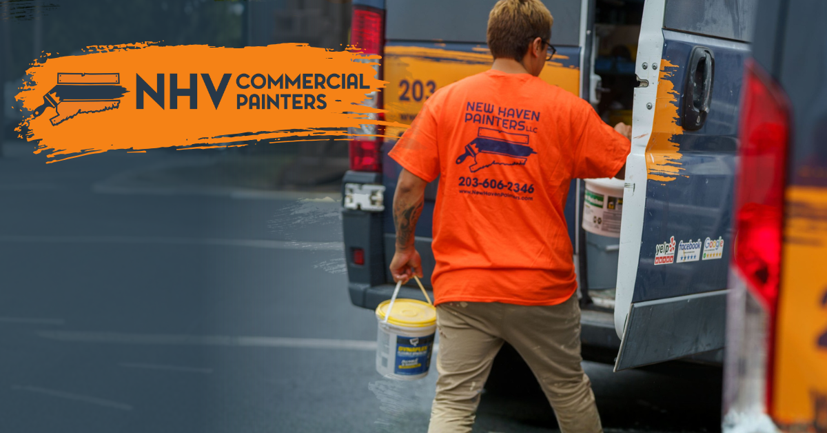 A painter in an orange shirt carries a bucket of paint toward a work van, with