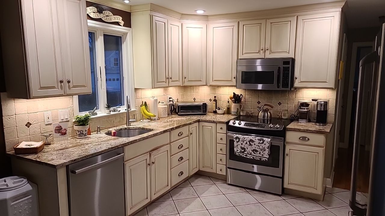 A kitchen with white cabinets , stainless steel appliances , granite counter tops and a window.