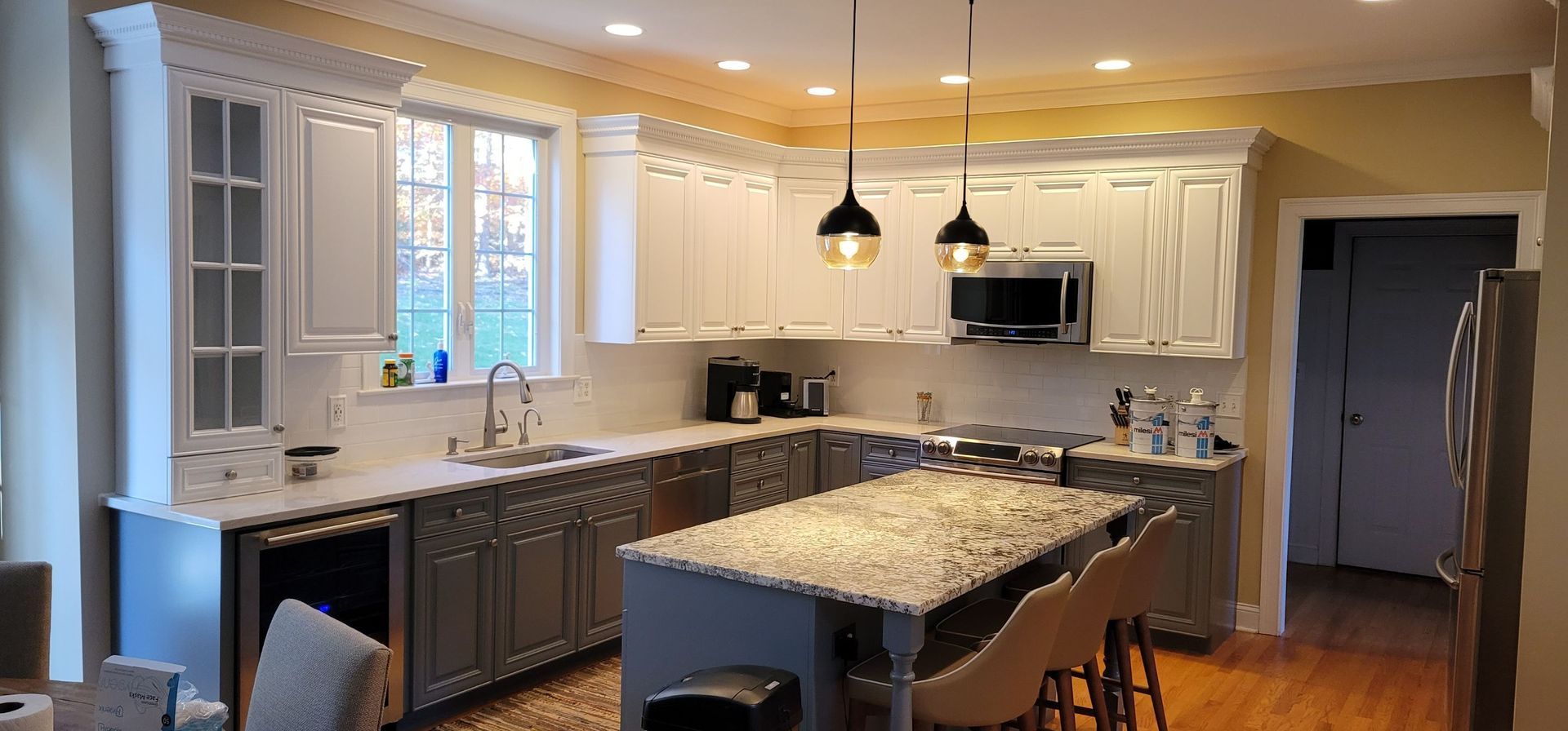 A spacious kitchen with white and gray cabinets, a large island, and pendant lights.