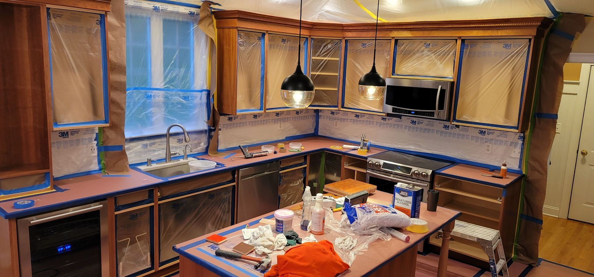 A kitchen is being painted with blue tape.