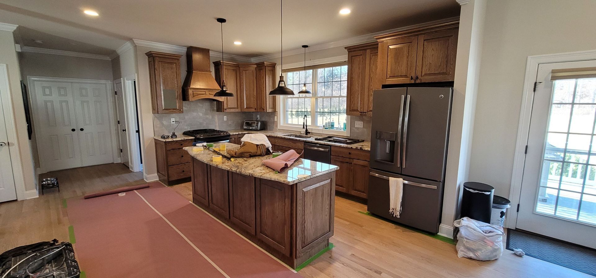 A kitchen with stainless steel appliances and wooden cabinets is being remodeled.