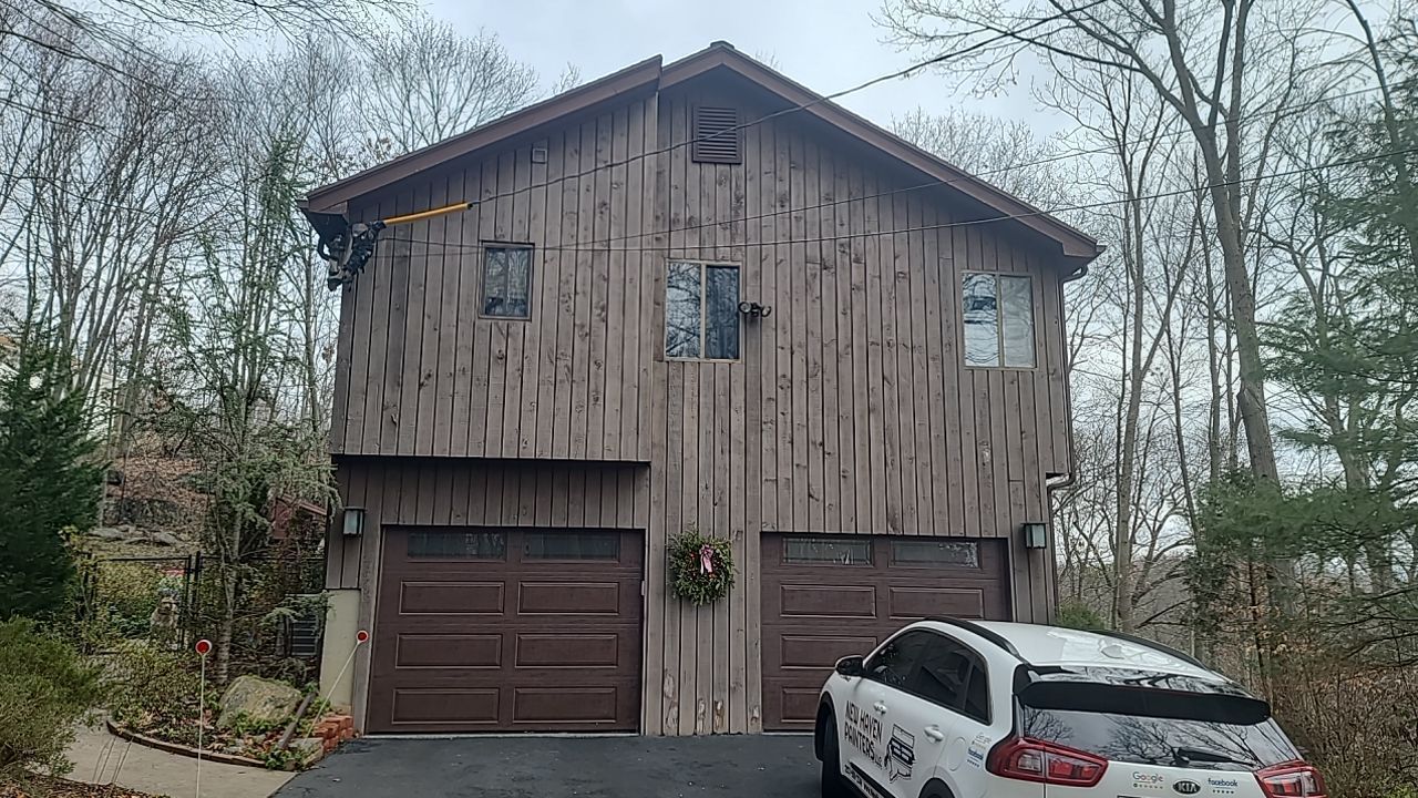 A car is parked in front of a wooden garage.