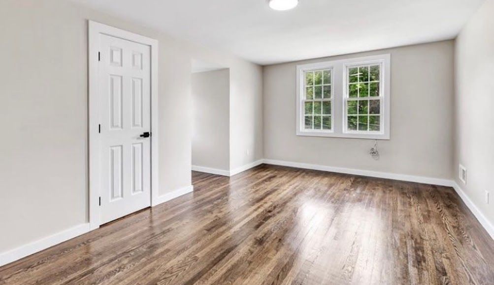 An beautiful empty living room with hardwood floors and two windows.