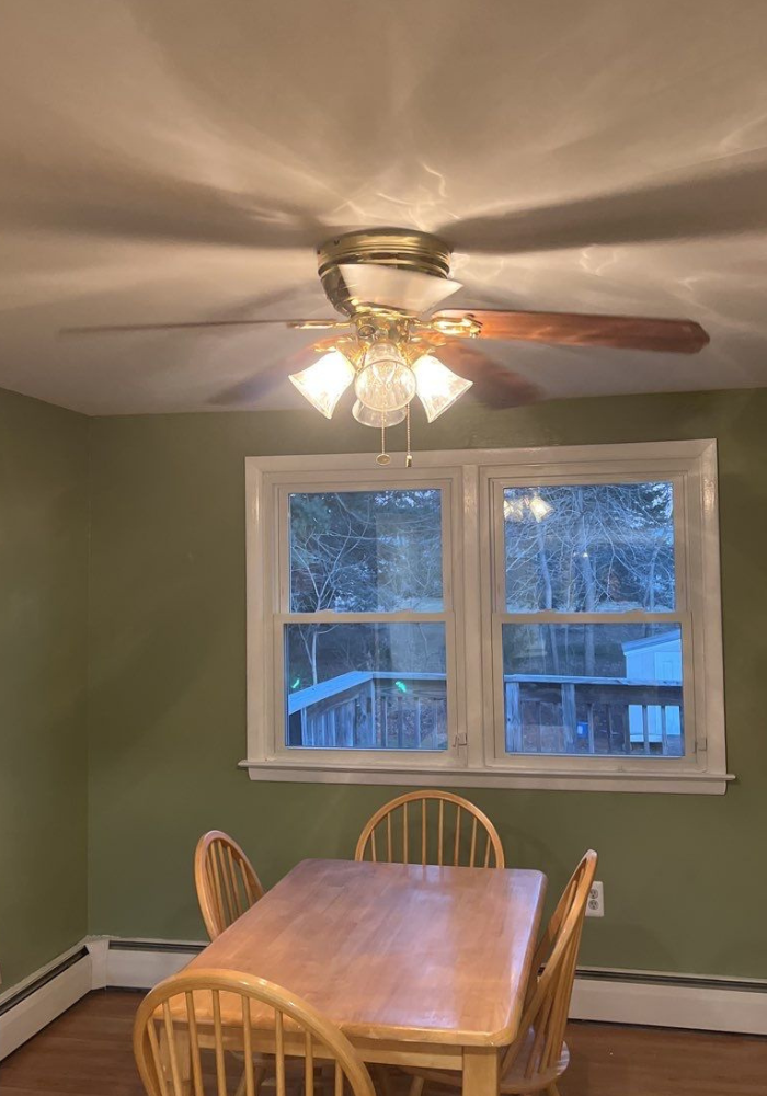 A dining room with a table and chairs and a ceiling fan.