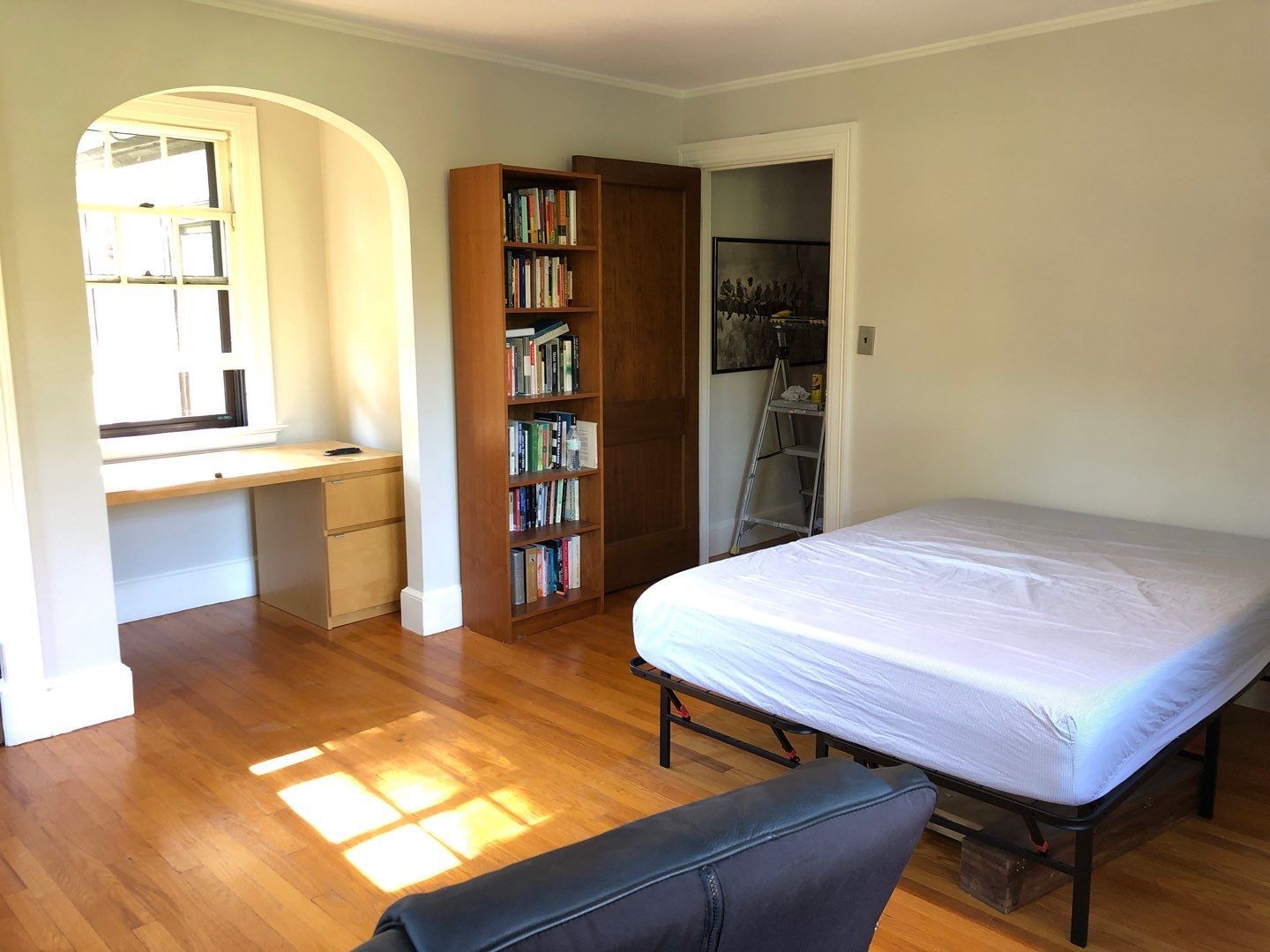 A bedroom with a bed , couch , desk and bookshelf.