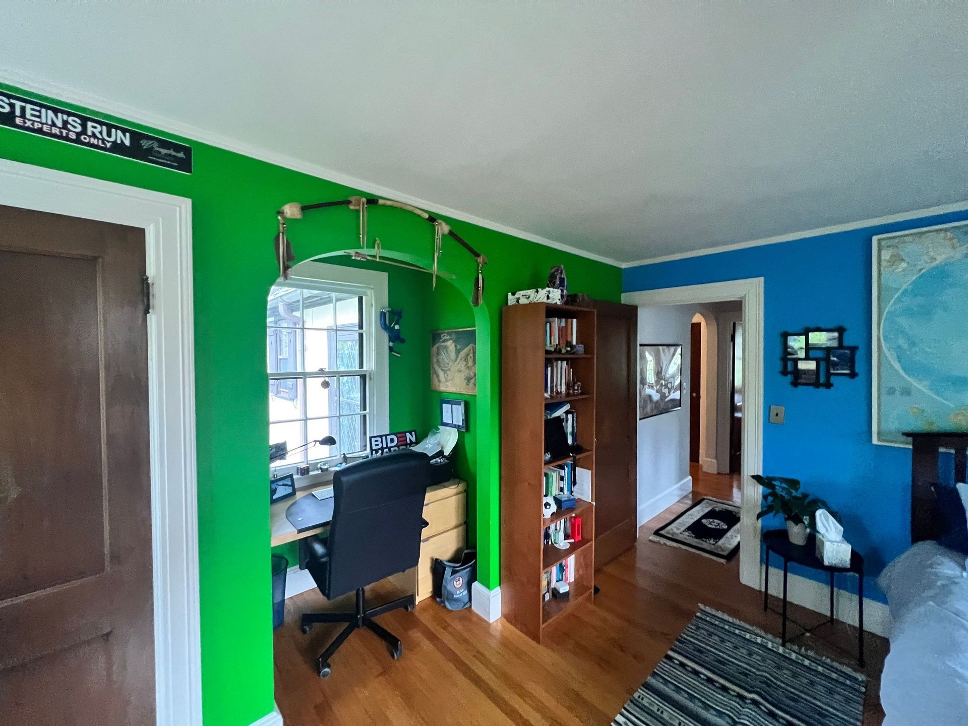 A room with green walls and blue walls has a desk and chair.