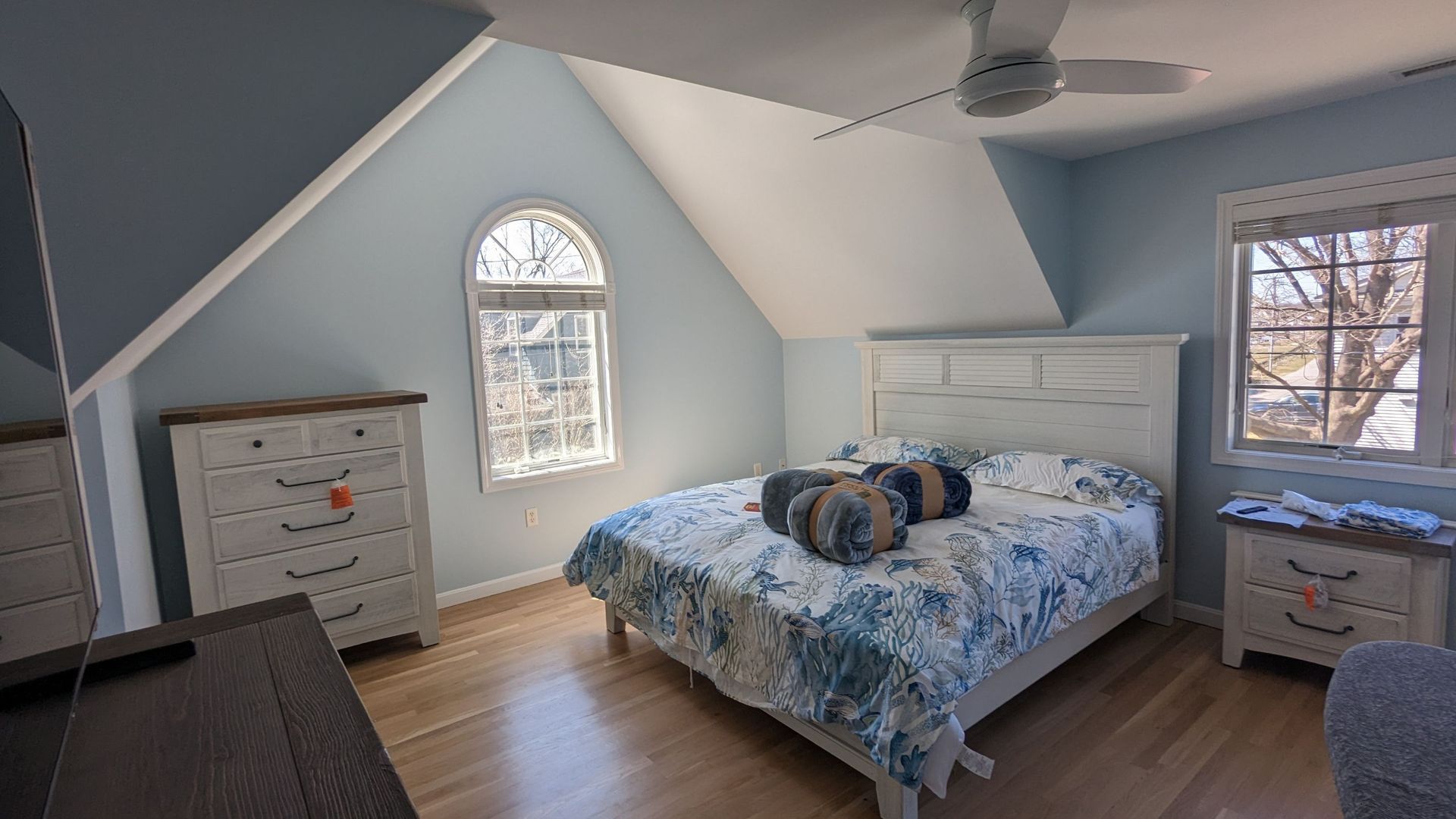 A bedroom with a bed , dresser , nightstand , and ceiling fan.