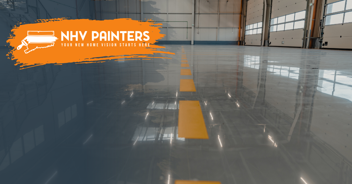 Glossy gray warehouse floor with yellow center lines and NHV Painters logo in the corner