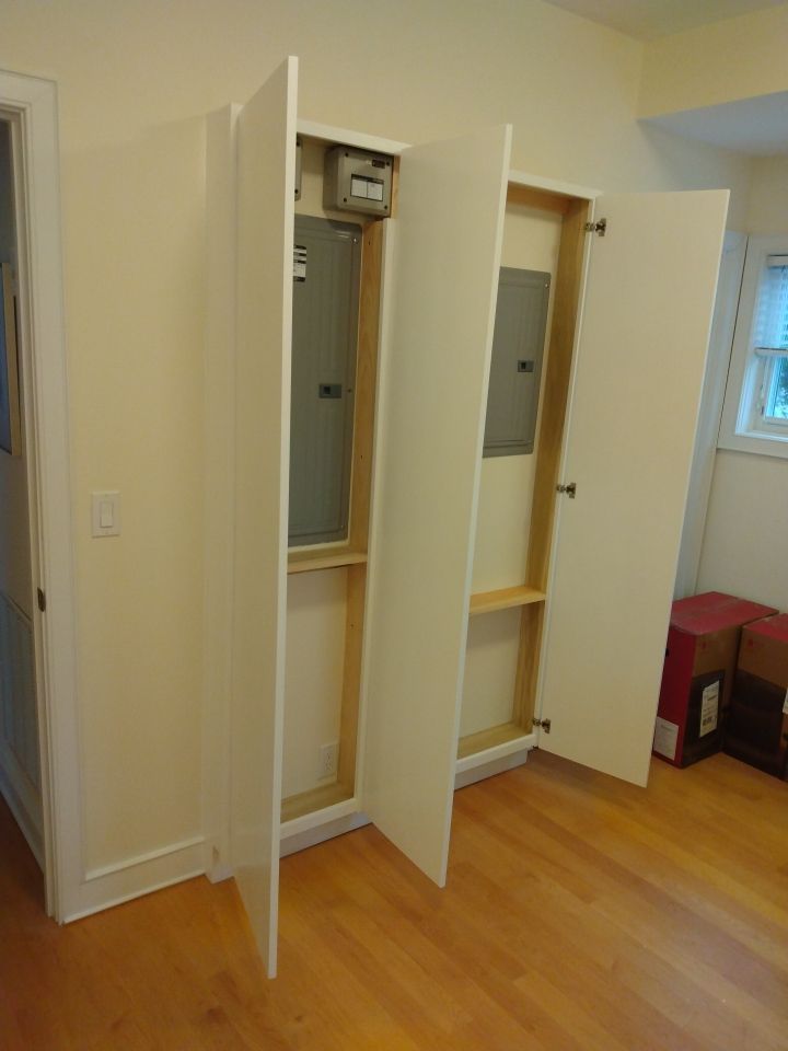 A room with hardwood floors and a white cabinet with the doors open.