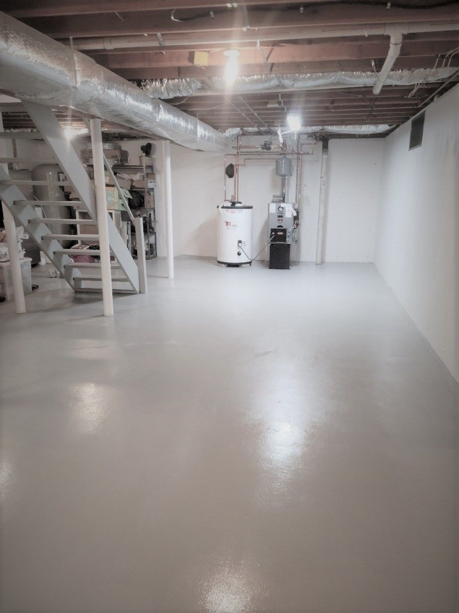 An empty basement with stairs and a water heater.