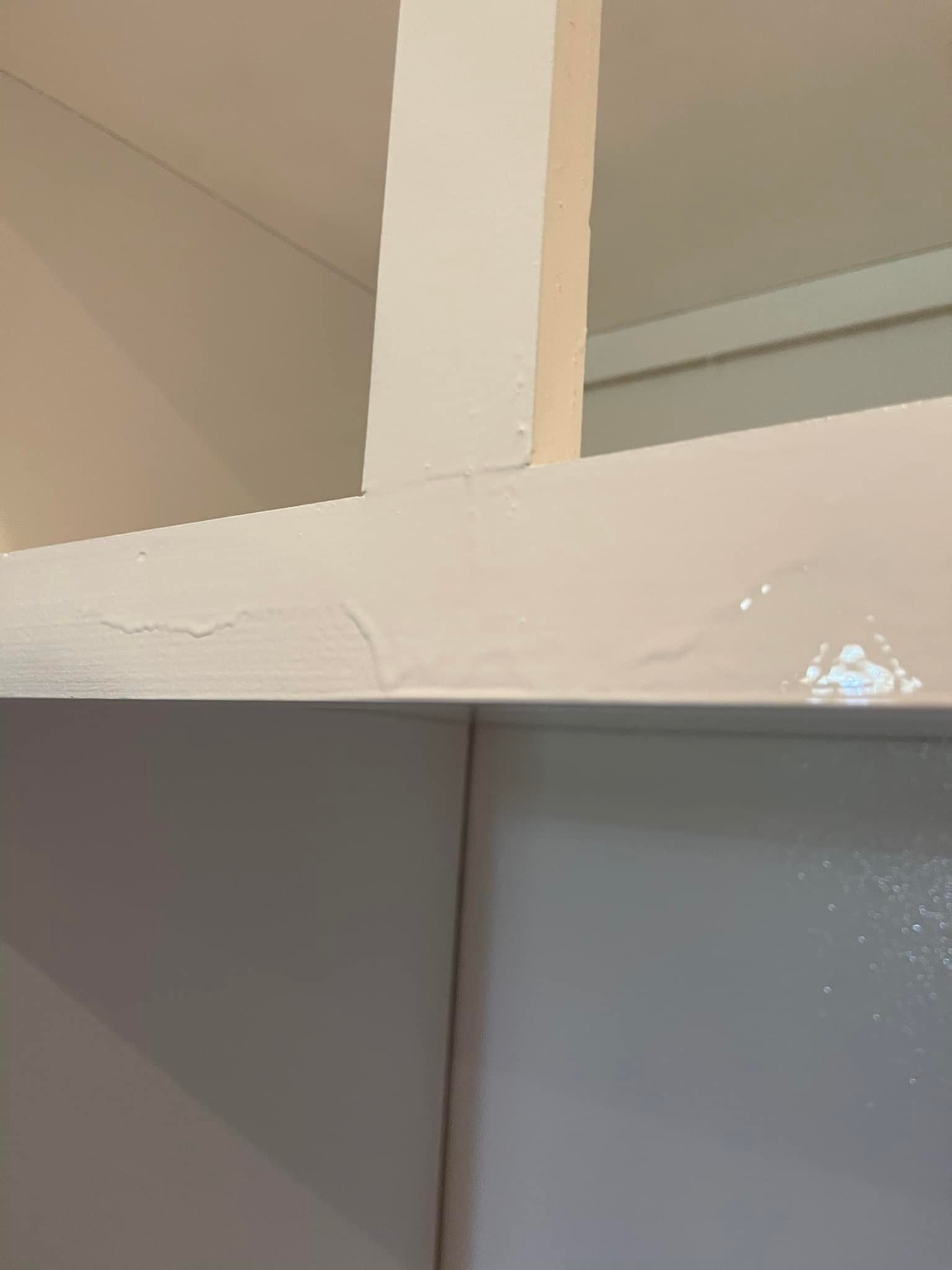 White painted wooden beams showing paint cracking in the corner.