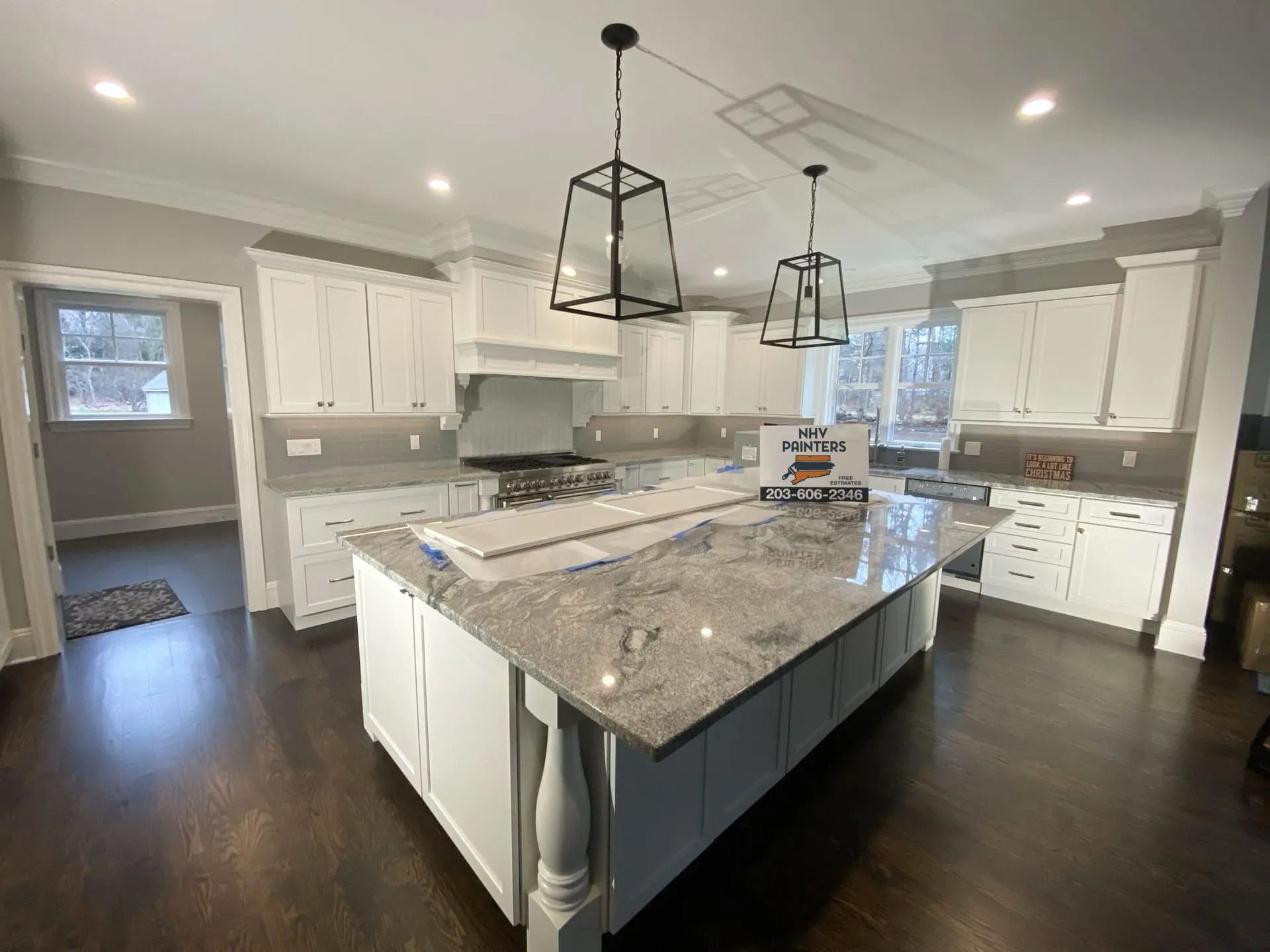 Spacious kitchen with white cabinets, granite countertops, and a large island. Two black pendant lights hang over the island.