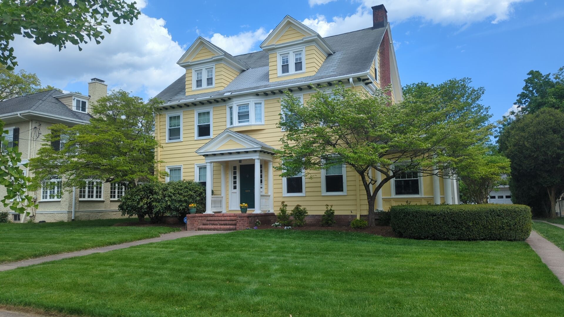 A large yellow house with a lush green lawn in front of it