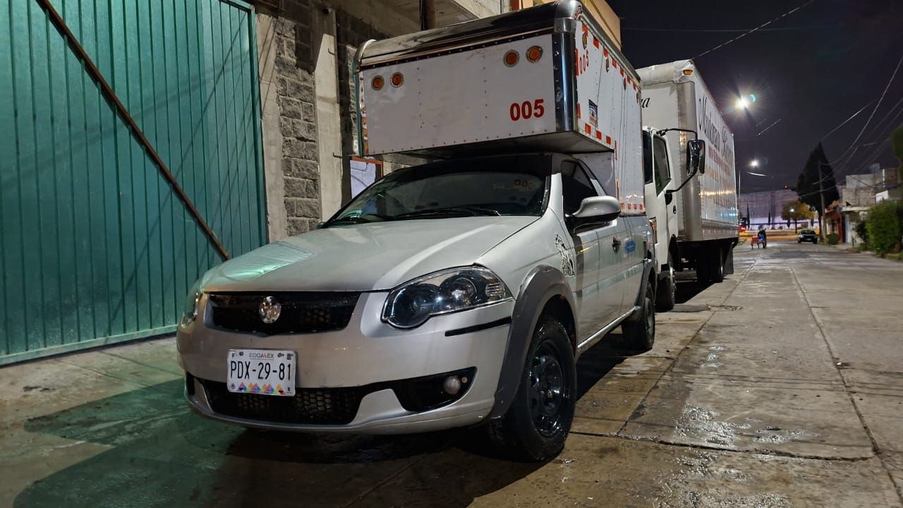 Camión Fiat plateado con un gran contenedor blanco en una calle por la noche.