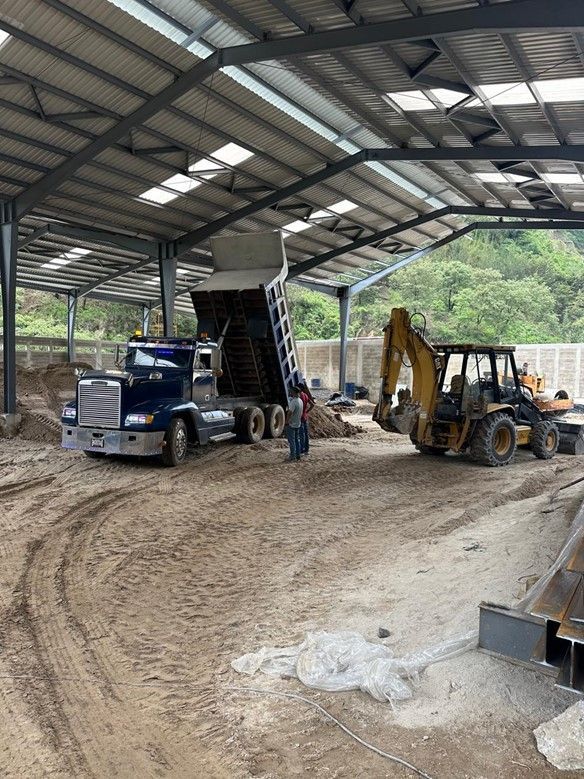 Un camión volquete se está cargando con tierra en un almacén.