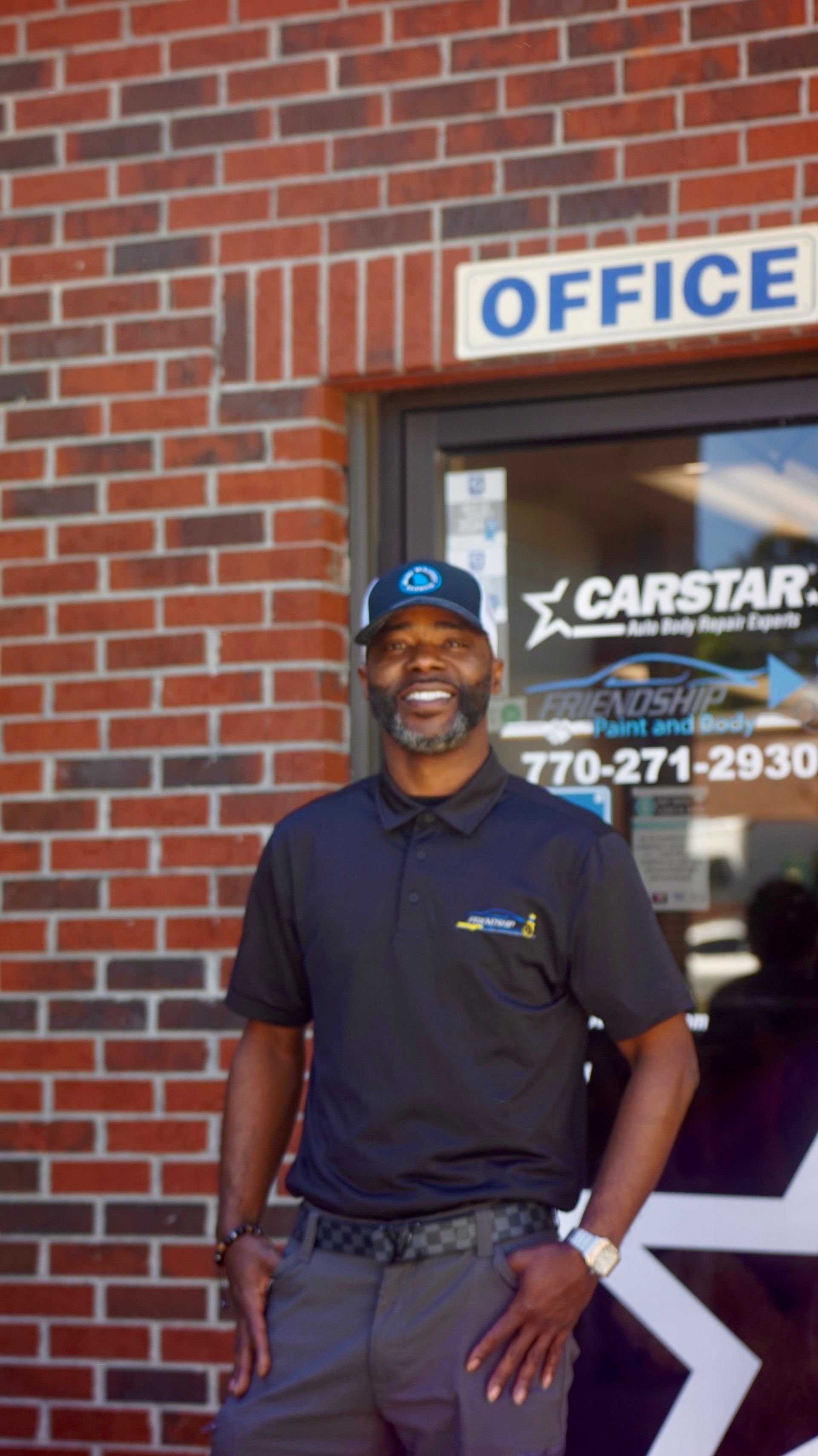Man standing smiling outside an office entrance with a CARSTAR sign above the door