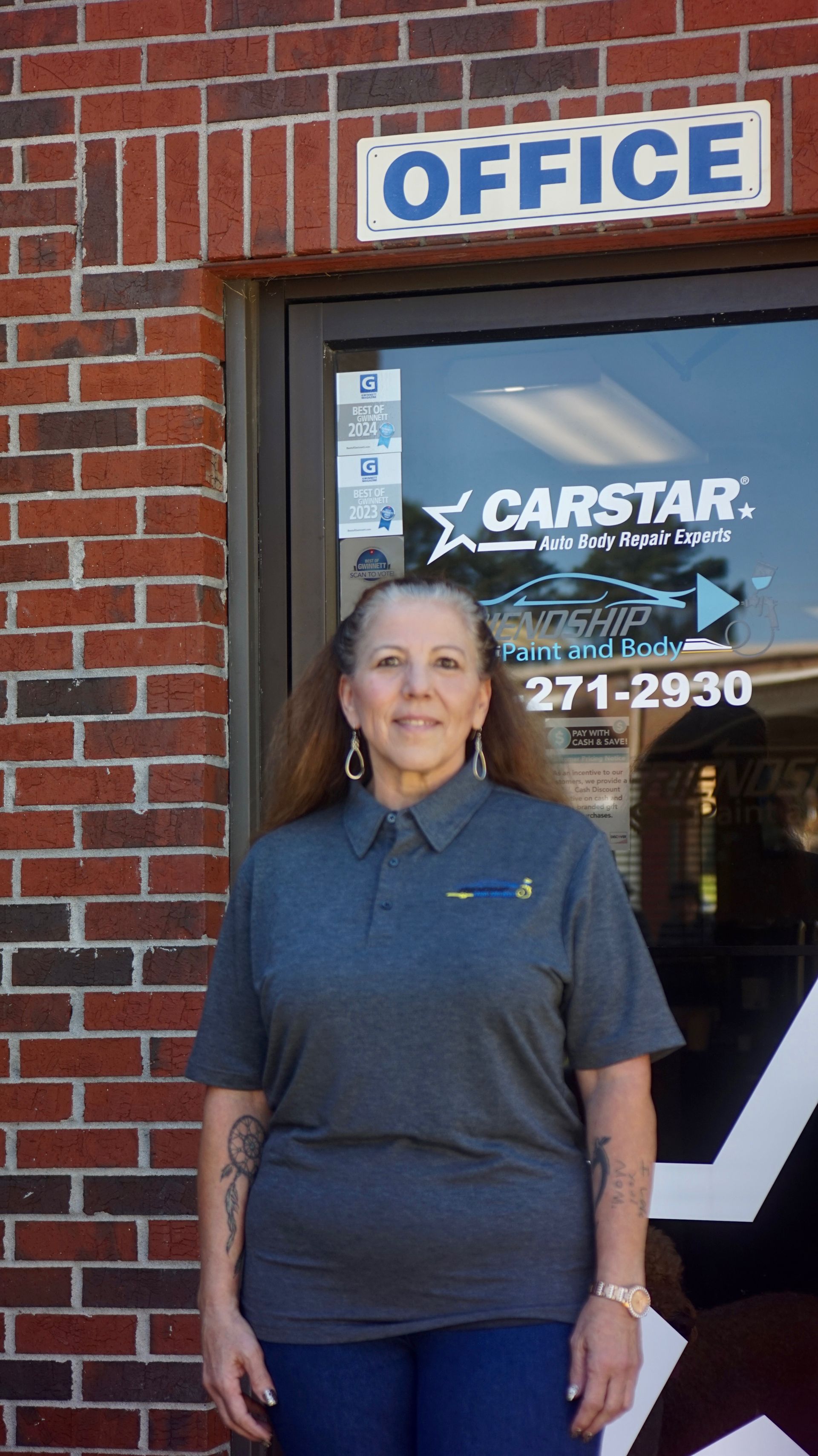 Person standing outside an office door with a CARSTAR sign above it