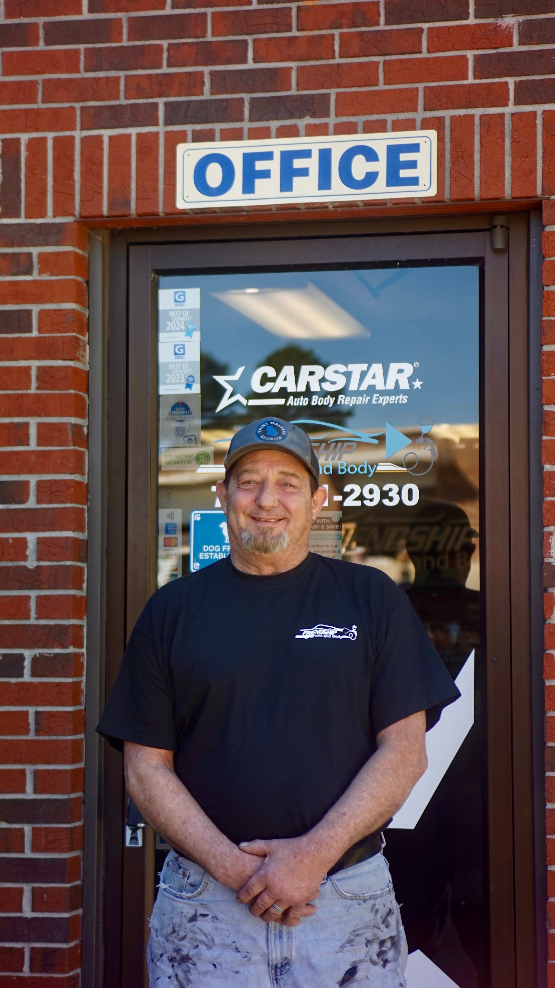 Man standing outside a CARSTAR office entrance beneath a blue “OFFICE” sign