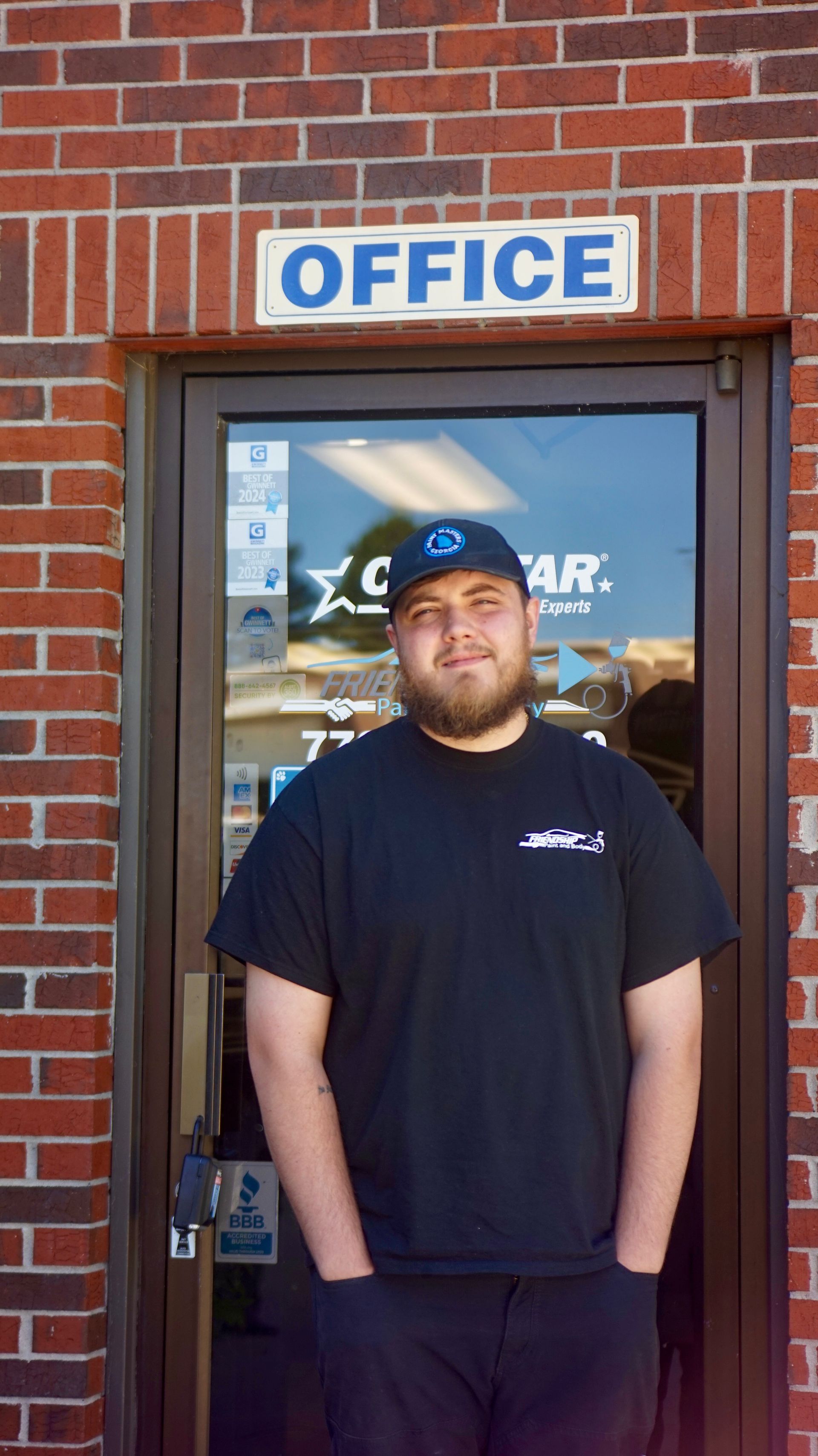 Man standing in front of an office doorway with an “OFFICE” sign above it.